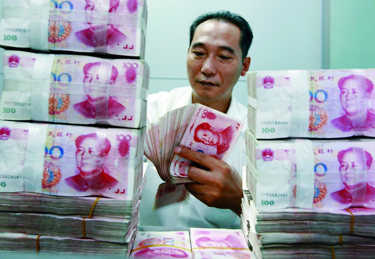 A Chinese bank staff member counting stacks of 100-yuan notes at a bank in Huaibei, east China’s Anhui province.