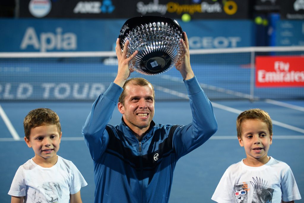 Gilles Muller of Luxembourg holds up his trophy with his sons Lenny and Nils after beating Daniel Evans of Britain in the men's singles final match at the Sydney International tennis tournament in Sydney on January 14, 2017.  AFP / Peter PARKS