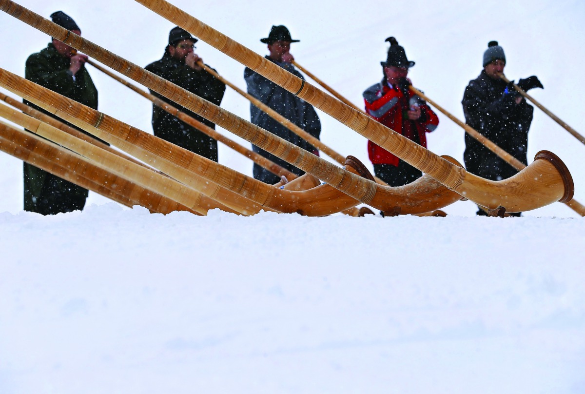Alphorn players blow their instruments as snow falls on the Fellhorn mountain near Oberstdorf, southern Germany, during a ceremony to inaugurate a new chairlift on January 13, 2017. / AFP / dpa / Karl-Josef Hildenbrand
