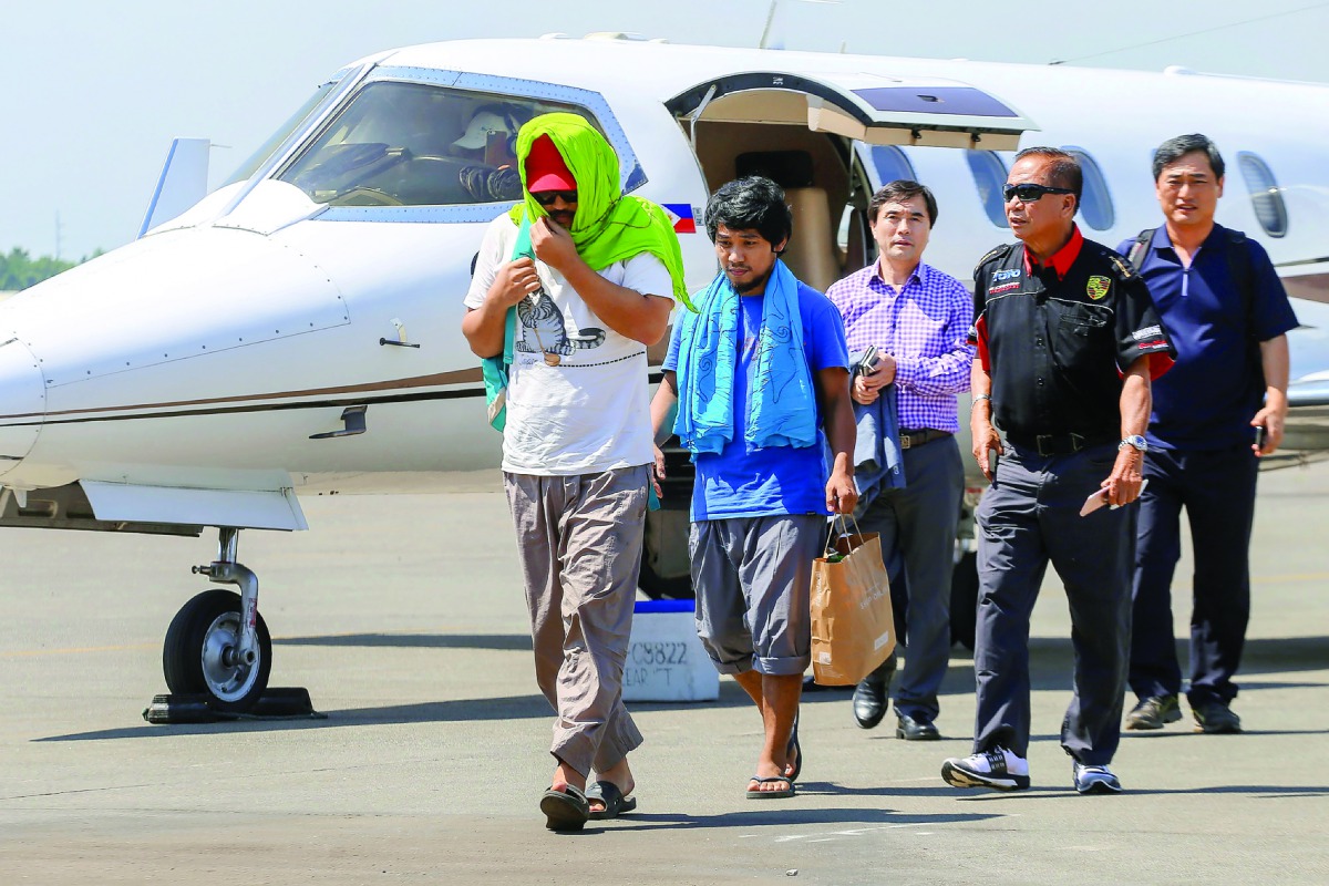Captain Chul Hong Park (left), a South Korean national, and 2nd officer Glenn Alindajao (second left) arrive in Davao City with Philippine Peace Adviser Secretary Jesus Dureza, yesterday.