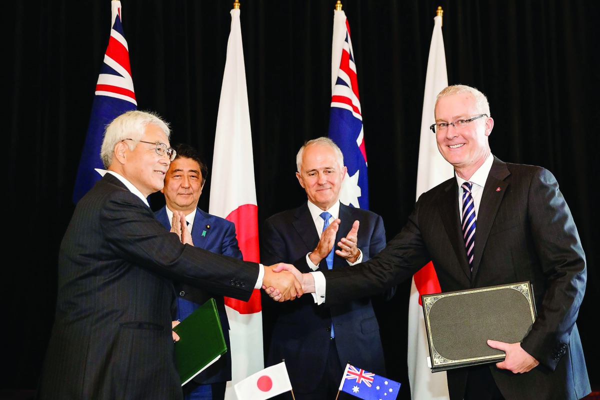 Japan's Prime Minister Shinzo Abe and his Australian counterpart Malcolm Turnbull applaud as Japan's Ambassador to Australia Sumio Kusaka (left) and Australia's Ambassador to Japan Bruce Miller (right) shake hands during a joint signing ceremony at the co