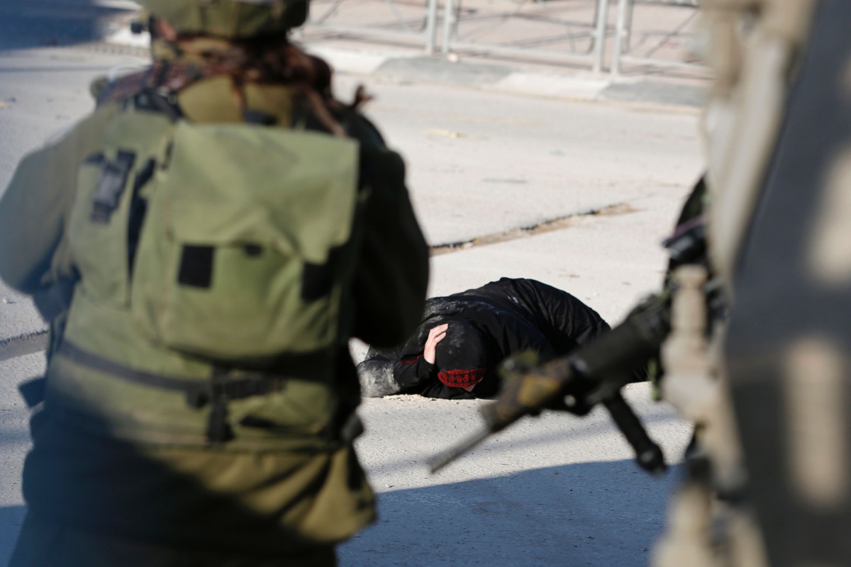 FILE PHOTO: A Palestinian woman lies on the ground after she was shot and wounded by Israeli security forces  at Qalandia checkpoint between Jerusalem and the occupied West Bank on December 30, 2016 (AFP /ABBAS MOMANI) 