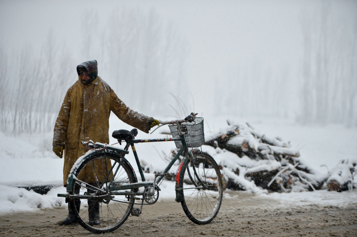 A Kashmiri man rests after riding a bicycle during a snowfall in the outskirts of Srinagar on January 17, 2017. Kashmir has been cut off from the rest of the country after heavy snowfall closing the 294km Jammu-Srinagar national highway, the only road lin