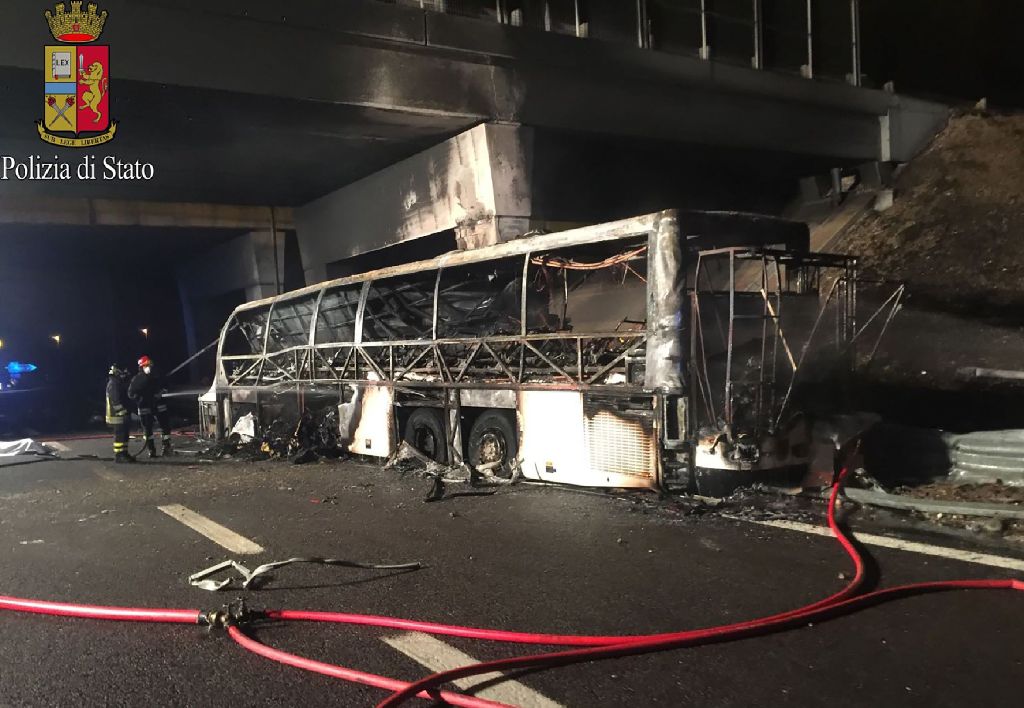 A handout photo provided by the Polizia di Stato on January 21, 2017 shows firefighters standing next to the burnt out wreckage of a bus on a motorway near Verona, after the bus carrying Hungarian teenagers struck a pylon and burst into flames.  AFP / Pol