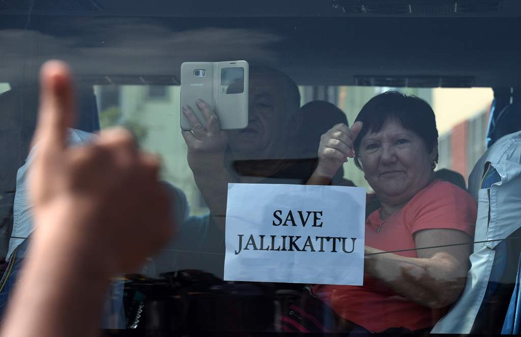 A foreign tourist raises her thumb and holds a placard against the car window as she passes students during a demonstration against the ban on the Jallikattu bull taming ritual and a call for a ban on animal rights orgnisation PETA, in Chennai on January 