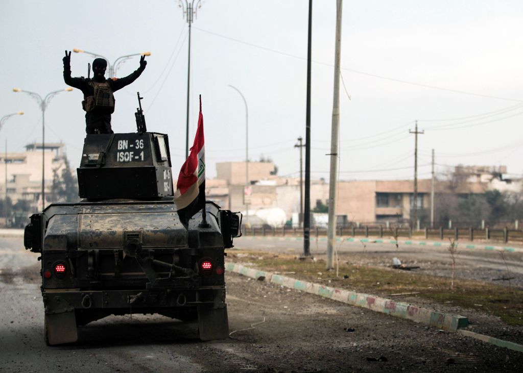 A member of the Iraqi counter-terrorism service (CTS) flashes the V-gesture as he stands atop a humvee patrolling the Andalus neighbourhood in the city of Mosul after its liberation from the Islamic state group (IS) control, during the ongoing military op