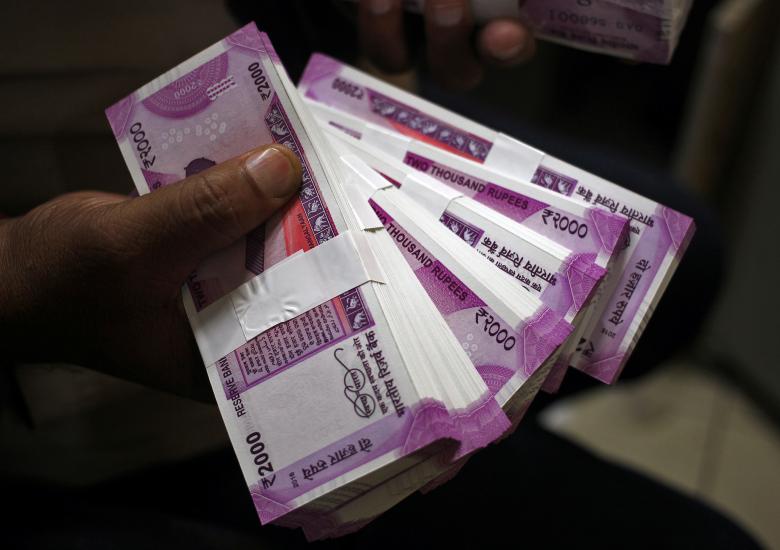 A cashier displays the new 2000 Indian rupee banknotes inside a bank in Jammu, India. (Reuters)