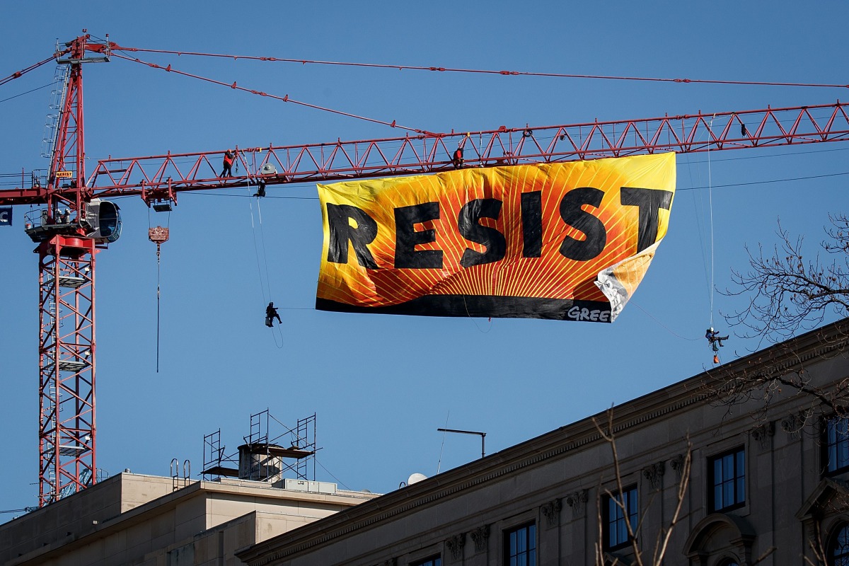Protesters unfurl a banner atop a crane at the construction site of the former Washington Post office building, January 25, 2017 in Washington, DC. The protestors are with the Greenpeace organization. Drew Angerer/Getty Images/AFP