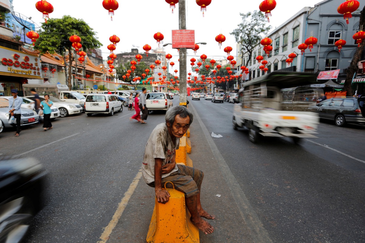 A man sits under lanterns and decorations on a street ahead of the Chinese Lunar New Year in Chinatown Yangon, Myanmar January 23, 2017. REUTERS/Soe Zeya Tun