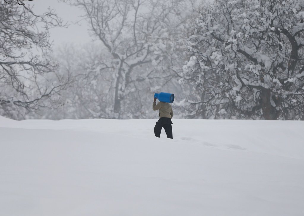 An Afghan man caries gas cylinder on his shoulder on the snowy day on the outskirts of Kabul, Afghanistan January 24, 2017. REUTERS/ Omar Sobhani