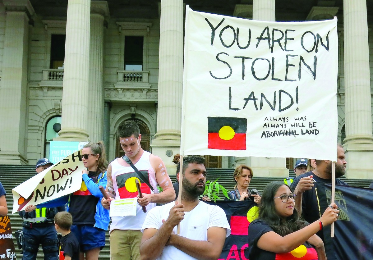 Aboriginal protesters hold signs as they demonstrate outside the Victorian State Parliament on Australia Day, in Melbourne, yesterday.