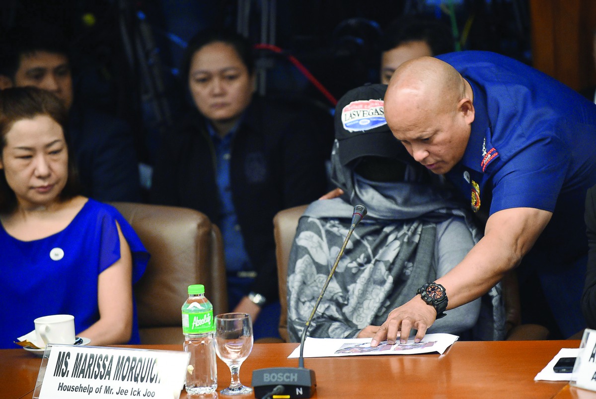 Philippine Police Chief Ronald Dela Rosa shows photos to Marissa Morquicho, the househelp of Jee, as they appear at a Senate hearing into Jee's death, in Manila, yesterday.