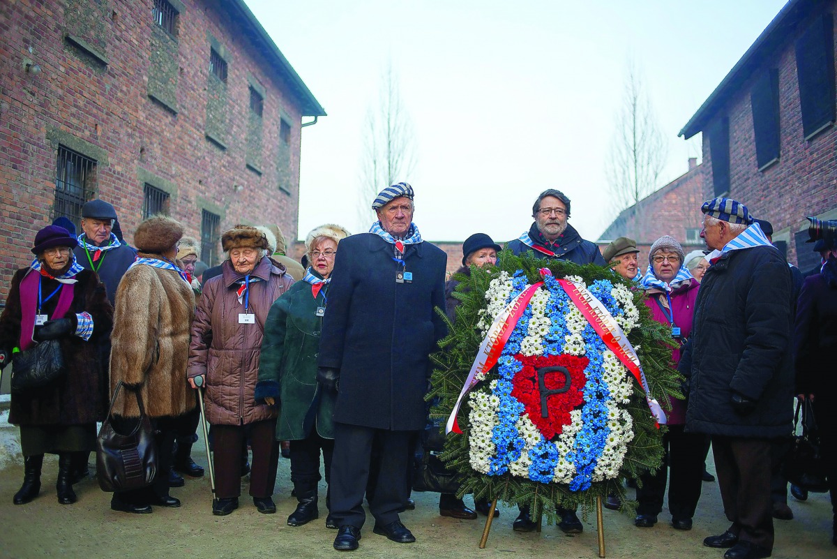 Survivors stand before laying a wreath in front of the 