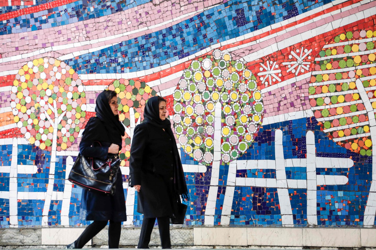 Two Iranian women walk along a street past a mosaic mural on Jaunary 14, 2017 (AFP / Atta Kenare) 