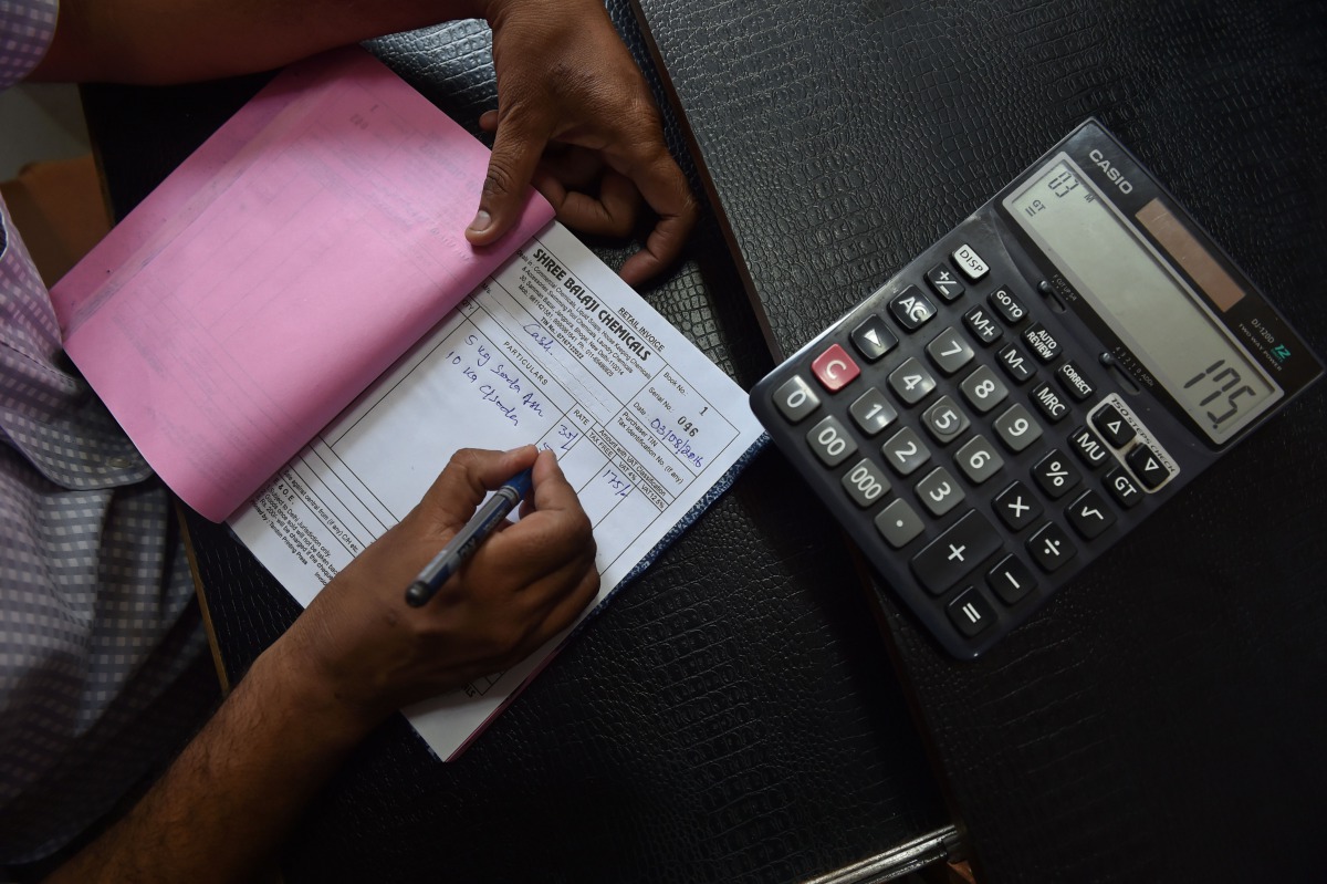 An Indian shopkeeper prepares a bill for a customer at his shop in New Delhi on August 3, 2016 (AFP / SAJJAD HUSSAIN) 