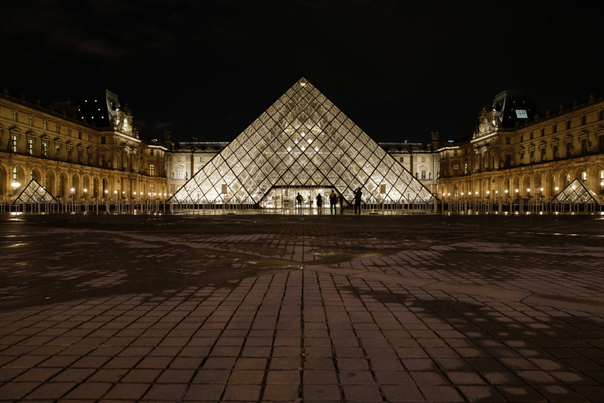 People stand outside the Louvre Pyramid of the Louvre museum at night on February 3, 2017, in Paris, after a French soldier patrolling at the Louvre shot and seriously injured a machete-wielding attacker earlier.