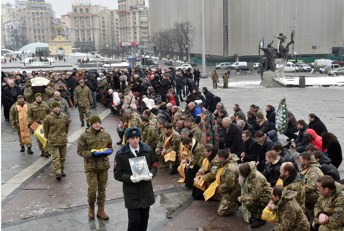 People kneel as servicemen carry a coffin with the body of an Ukrainian serviceman who died during fighting in the eastern Ukrainian town of Avdiivka, in Donetsk region, during obsequies on Independence Square in Kiev on February 3, 2017. (AFP / Sergei SU