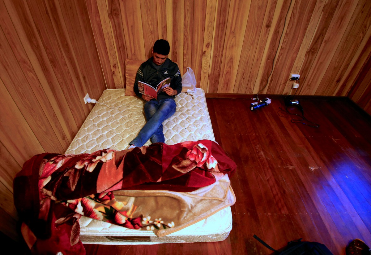FILE PHOTO: Ali Rasooli, a refugee from Afghanistan, sits on his mattress reading a book in a house he rents with other refugees in the western Sydney suburb of Guildford Australia, July 17, 2016 (REUTERS / David Gray) 