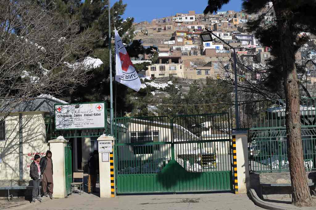 Afghan bystanders gather as The International Committee of the Red Cross (ICRC) flag flies at half-mast at the entrance to the ICRC Orthopaedic Centre in Kabul on February 9, 2017. AFP / SHAH MARAI
