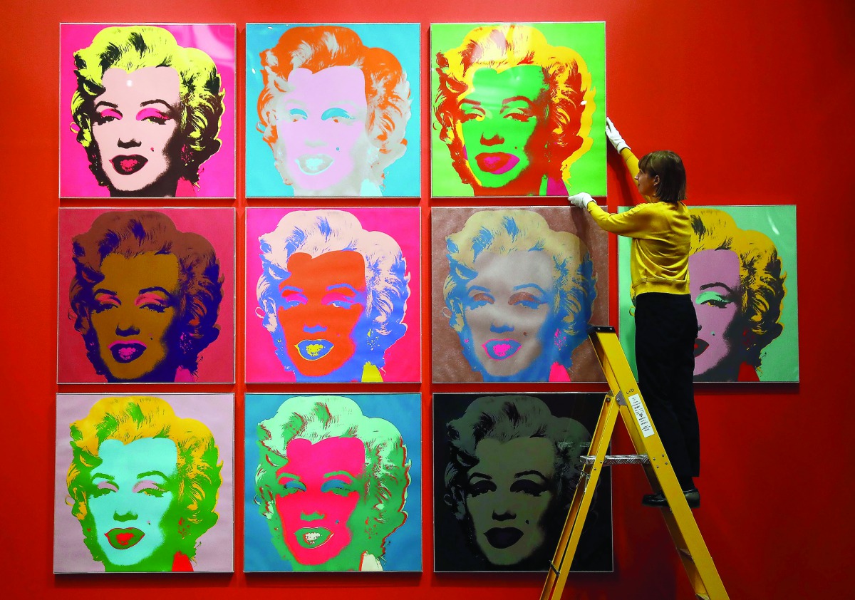An employee poses with screen prints of Marilyn Monroe by Andy Warhole as part of the exhibition”American Dream: pop to the present” at British Museum in London
