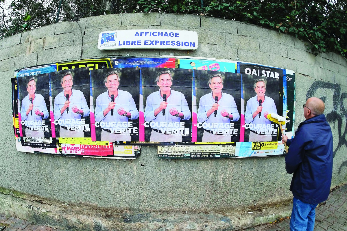 A man pastes electoral posters of French presidential election candidate Francois Fillon, on the streets of Marseille, yesterday.