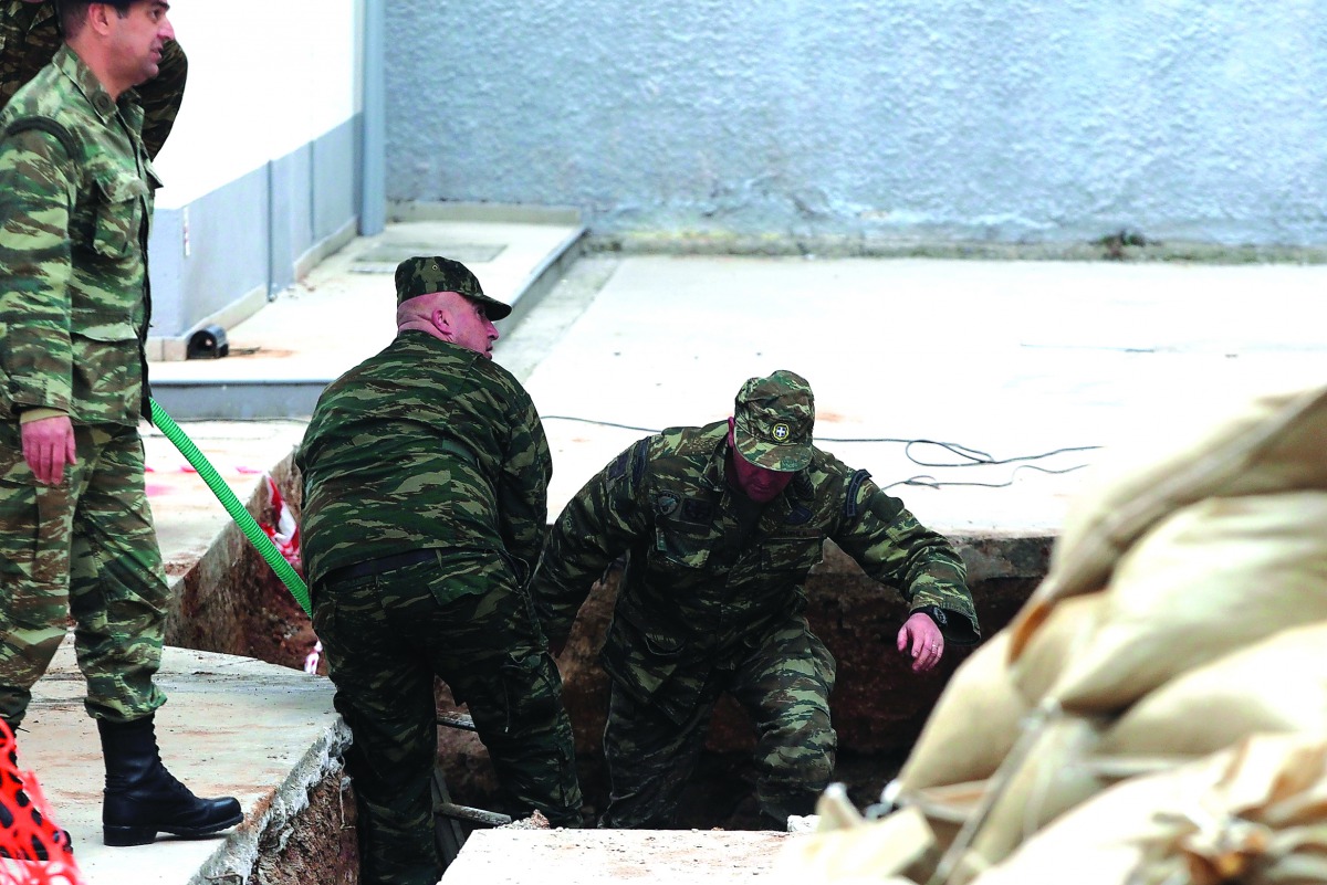 Soldiers jump into a hole to inspect a 250kg World War II bomb that was found during excavation works at a gas station in Thessaloniki, Greece, yesterday. Authorities are making arrangements to evacuate about 75,000 people ahead of efforts to defuse the b