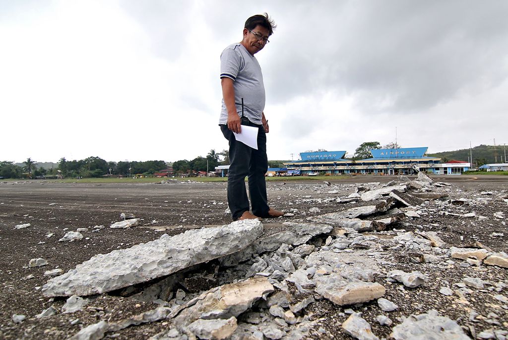 A man looks at the damaged runway of the dometic airport after a 6.5-magnitude earthquake struck overnight in Surigao City in southern island of Mindanao on February 11, 2017.  AFP / ERWIN MASCARINAS
