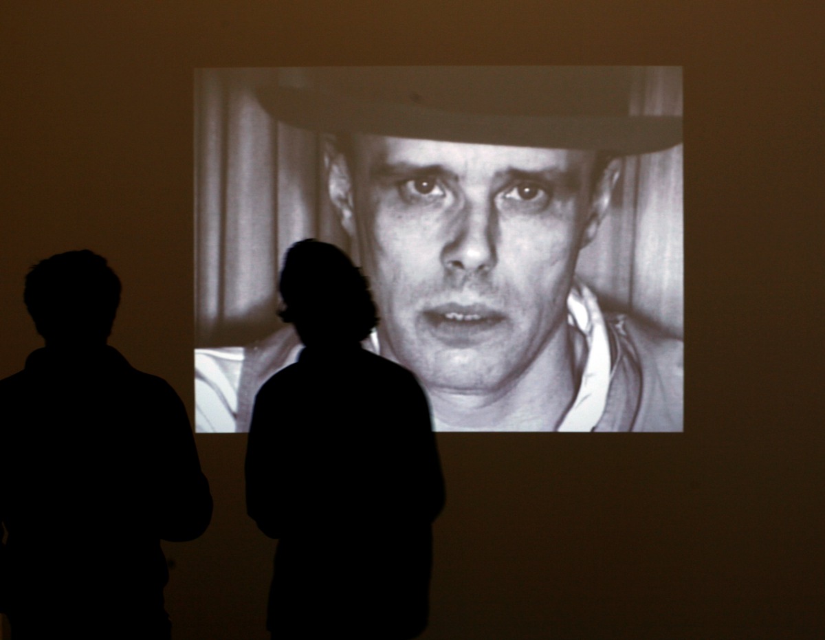 Visitors stand in front of the screen projecting videos of artist Joseph Beuys during the exhibition 'Beuys, We are the Revolution' at the The Hamburger Bahnhof museum for contemporary arts in Berlin October 1, 2008. REUTERS/Pawel Kopczynski