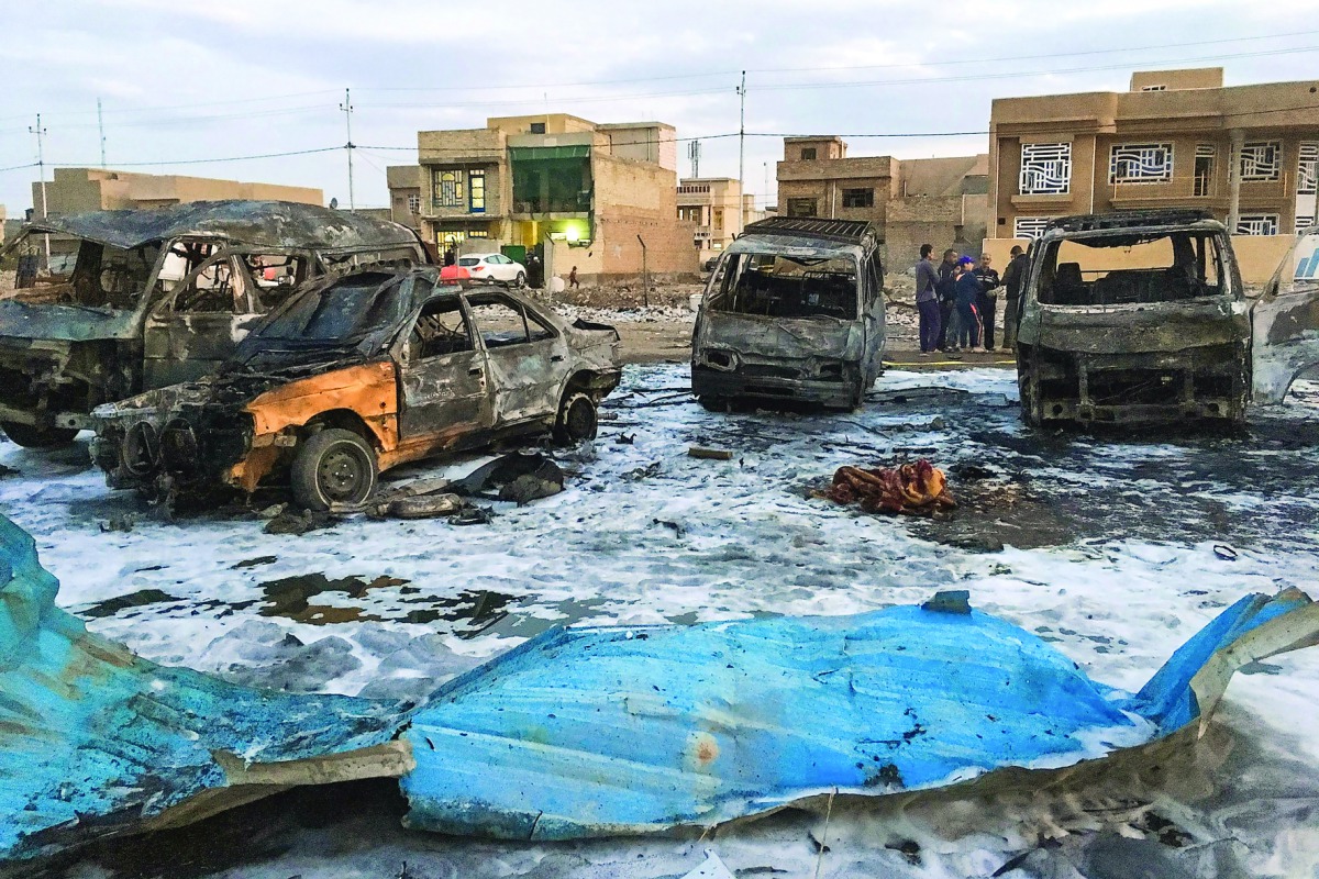 A picture taken with a mobile phone on February 16, 2017 shows burnt vehicles at the scene of a blast by a massive car bomb, which killed dozens in a used car market in southern Baghdad. The Amaq propaganda agency linked to the Islamic State group (IS), w