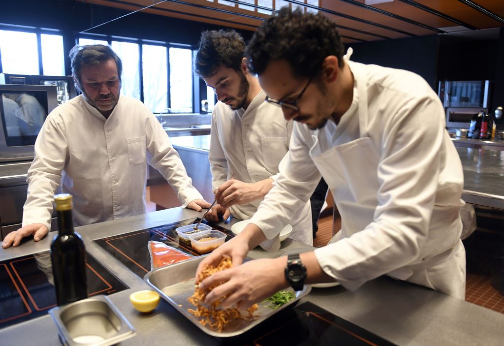 French Chef Michel Troisgros (L) cooks with his sons Cesar (R) and Leo (C), both chef, in the kitchen of their new restaurant on February 15, 2017, in Ouches, near Roanne, central France. AFP / PHILIPPE DESMAZES