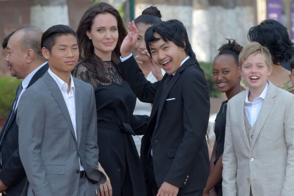 Hollywood star Angelina Jolie (3rd L) and her children including Maddox Jolie-Pitt (C) gesture to media in front of the royal residence for a meeting with Cambodian King Norodom Sihamoni in Siem Reap on February 18, 2017.AFP / TANG CHHIN SOTHY
