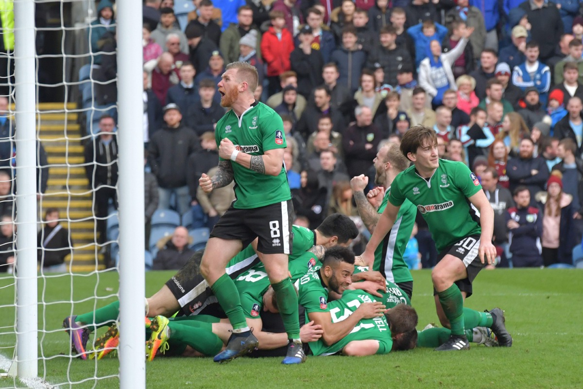 Lincoln City's English defender Sean Raggett (C) celebrates with teammates after scoring during the English FA Cup fifth round football match between Lincoln City and Burnley at the Sincil Bank stadium in Lincoln, eastern England, on February 18, 2017. (A