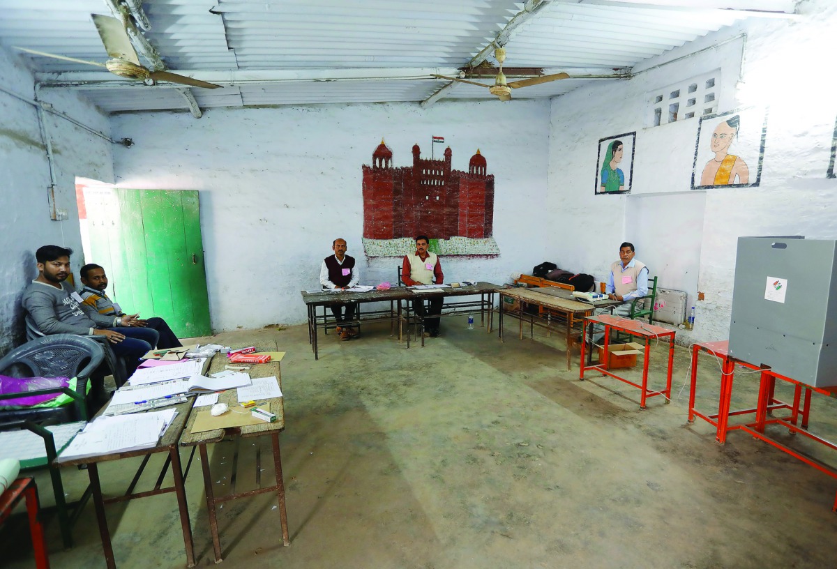 Polling officers wait for voters at a polling station during the state assembly election, in Lucknow, yesterday.