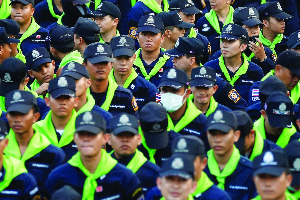 Police stand outside Dhammakaya Buddhist temple while followers defy orders to leave its grounds to enable police to seek out their former abbot in Pathum Thani, Thailand, yesterday.