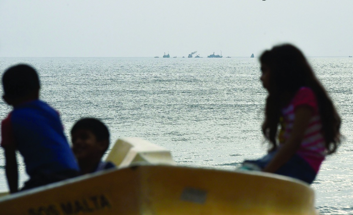 Sri Lankan children look on as navy boats search the waters off Katukurunda along the coast of Sri Lanka yesterday.