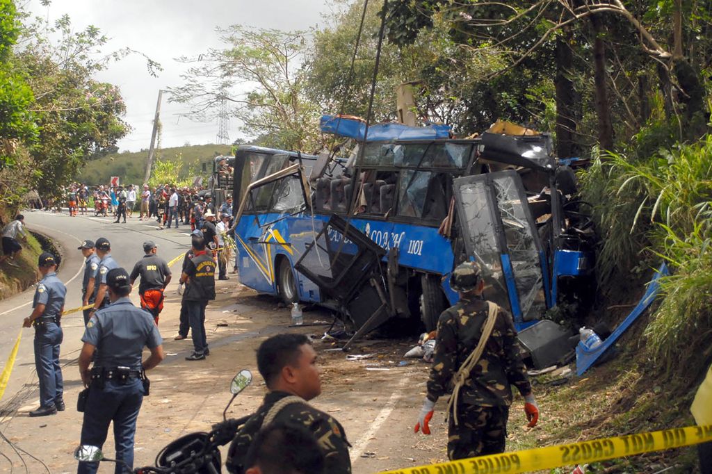 Police and soldiers stand guard next to a tourist bus which hit an electric post in Tanay town, Rizal province, east of Manila on February 20, 2017. AFP / STR
