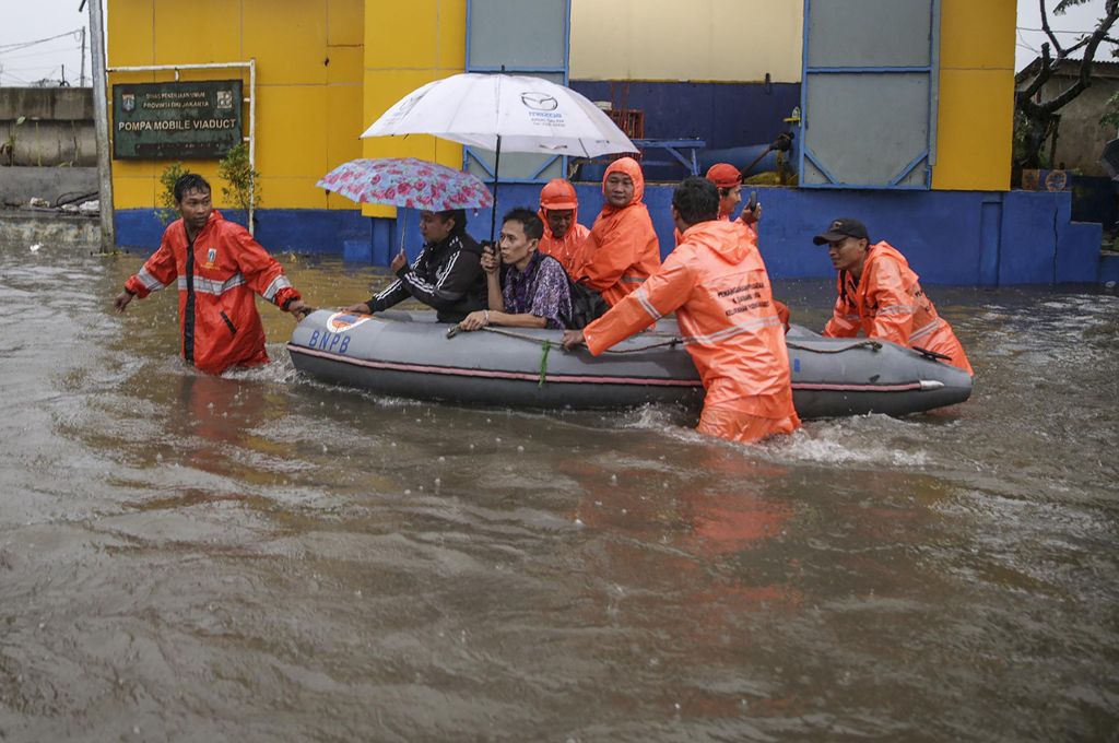 Flood-affected residents use a rubber boat in an inundated neighbourhood in Jakarta on February 21, 2017. Jakarta was hit by widespread flooding on February 21 after hours of torrential rain, with thousands of homes inundated, cars stranded and people for