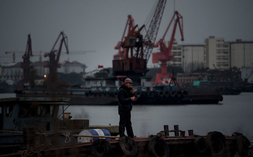 A man smokes a cigarette while standing on a boat in the Huangpu river in Shanghai on February 21, 2017. / AFP / Johannes EISELE
