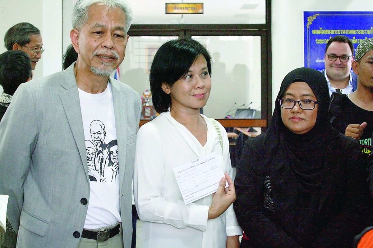 Pornpen Khongkachonkiet (centre), the chair of Amnesty International Thailand; Anchana Heemmina (right) and Somchai Homlaor show a document filed at the State Prosecutors office in Pattani, yesterday. 