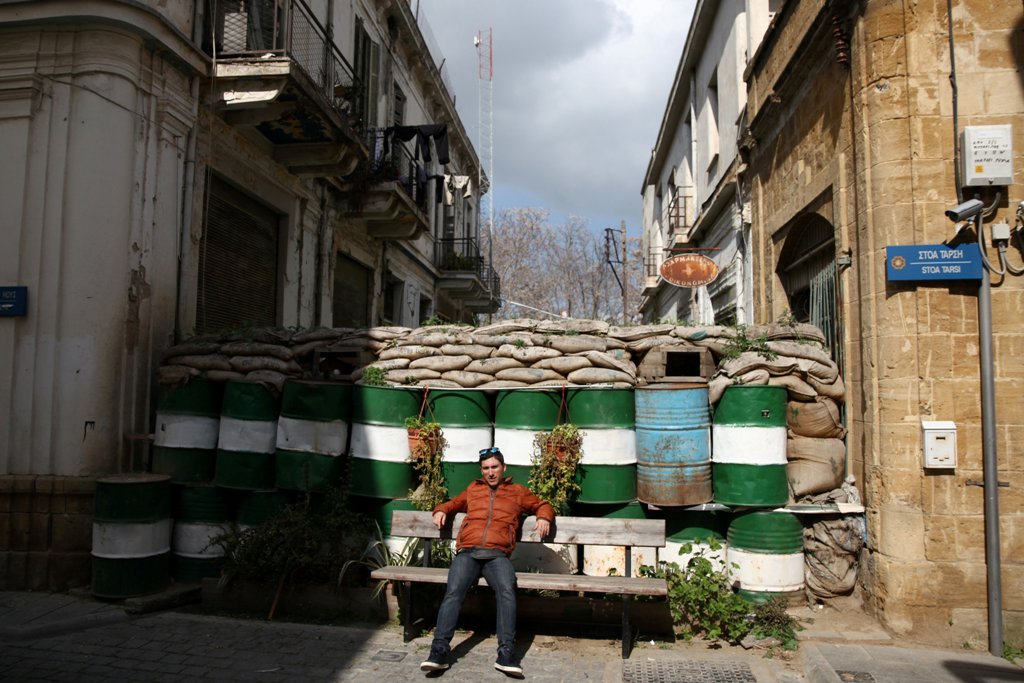 A man sits on a bench next to a barricade outside the U.N. buffer zone in Nicosia, Cyprus February 22, 2017. REUTERS/Yiannis Kourtoglou
