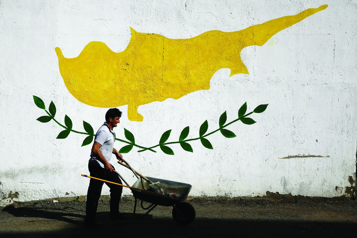 A man pushes a cart in front of a Cypriot flag painted on a wall in capital Nicosia, Cyprus, yesterday.