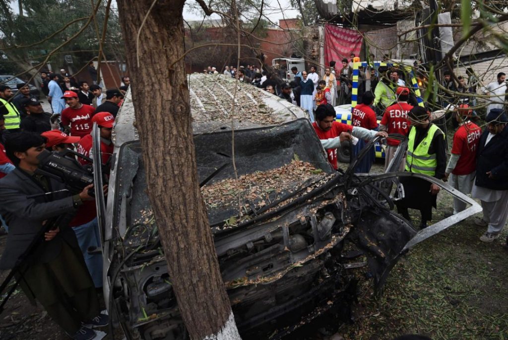 Pakistani volunteers examine the wreckage of a vehicle after a suicide bomb attack in Peshawar on February 15: ABDUL MAJEED / AFP.