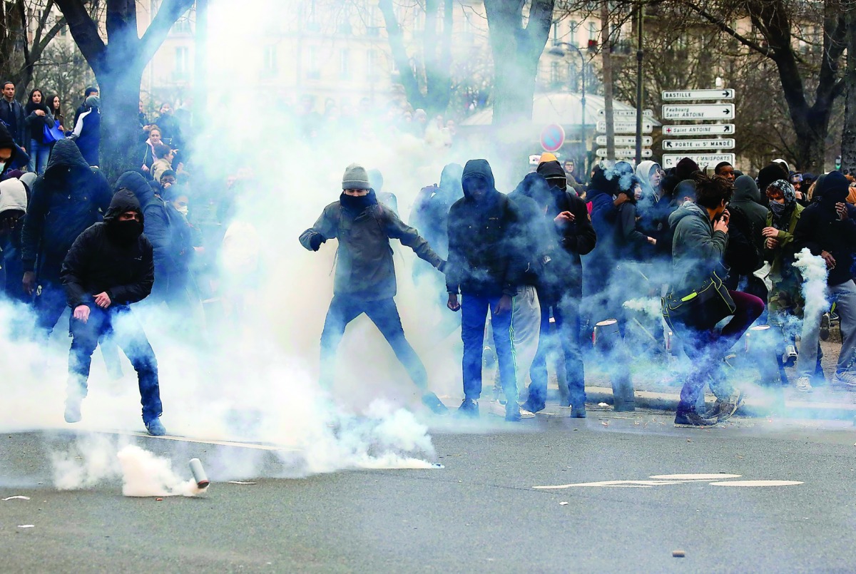 Clouds of tear gas surround youth as they face off with French police during a demonstration against police brutality in Paris, yesterday.