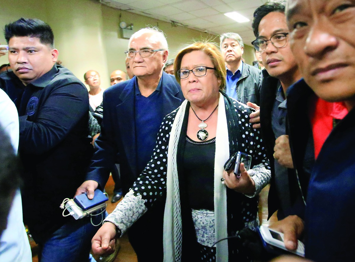 Philippine Senator Leila de Lima is escorted by the security personnel, at the Senate headquarters in Pasay City, yesterday.