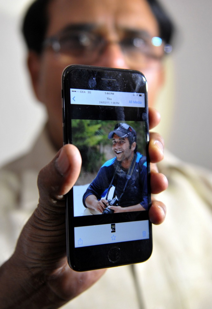 Indian man Jagan Mohan Reddy holds a smartphone with an image of his son Alok Madasani at his residence in Hyderabad on February 24, 2017, after Alok was injured in a shooting in the US state of Kansas. Alok and his friend Srinivas Kuchibhotla were in a b