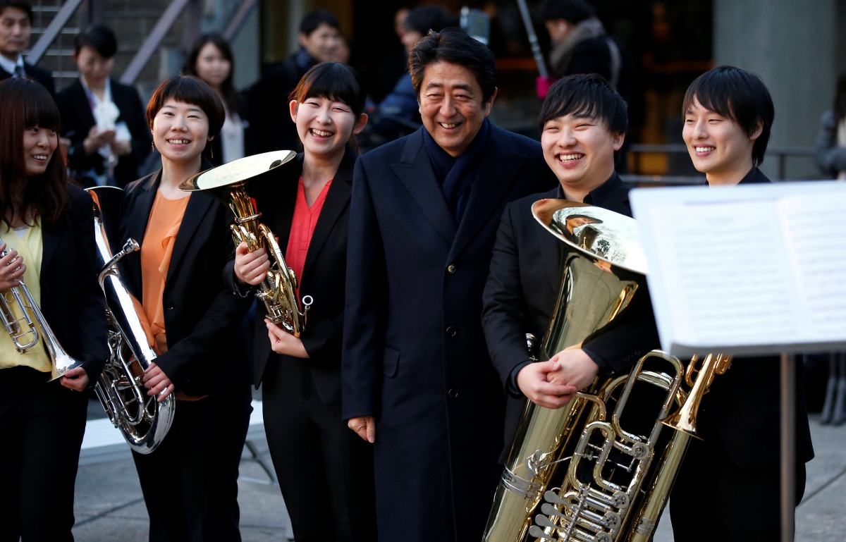 Japan's Prime Minister Shinzo Abe poses with musicians at a concert for Premium Friday, outside a museum in Tokyo, yesterday.