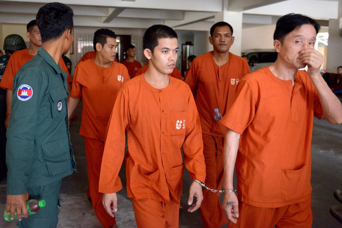 Ven Sopheap (centre) is escorted by a prison guard at the Phnom Penh Municipal Court, yesterday. 