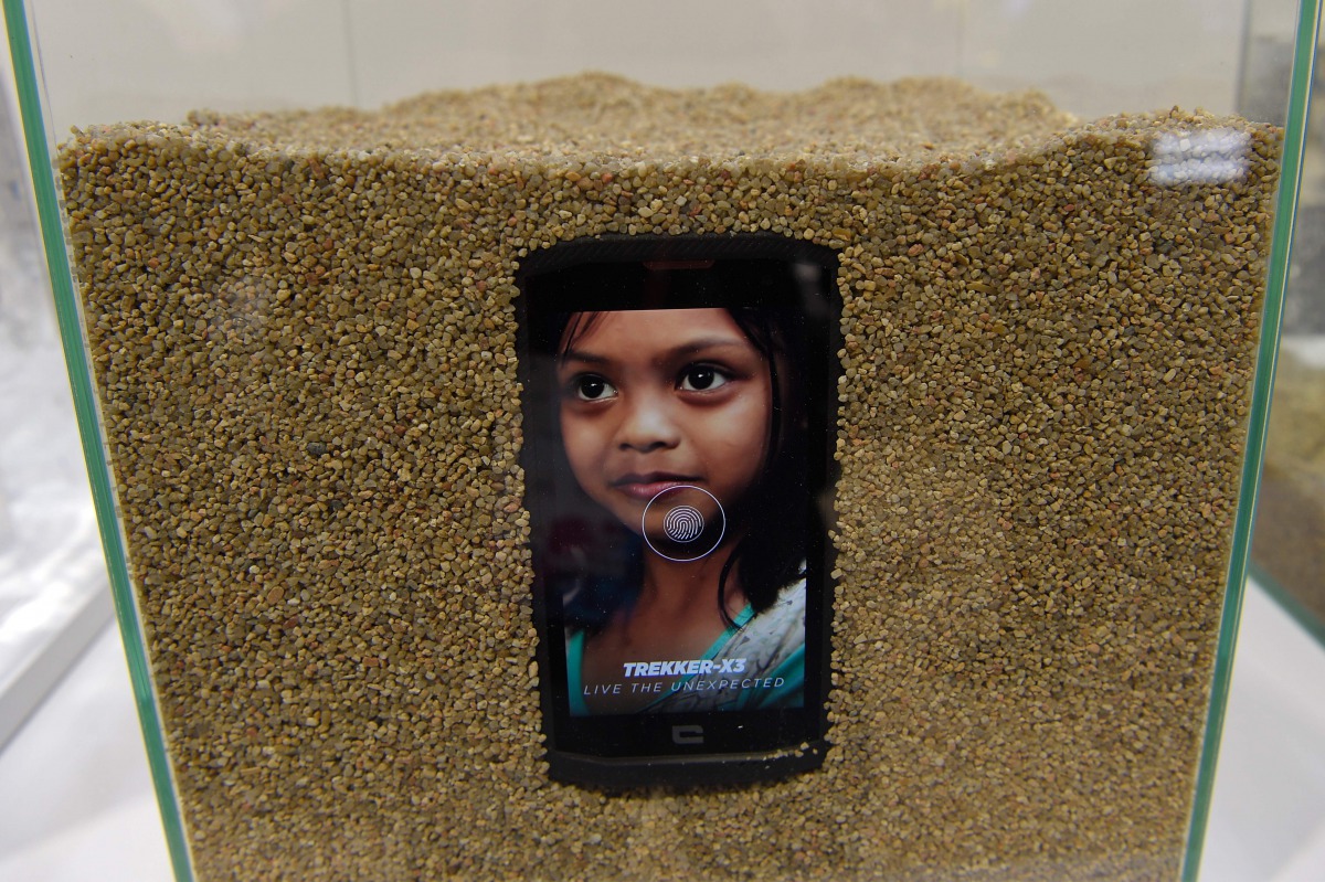 This picture shows a Crosscall Trekker-X3 smartphone inside a tank full sand on the first day of the Mobile World Congress in Barcelonaon on February 27, 2017 in Barcelona. Phone makers will seek to seduce new buyers with artificial intelligence functions