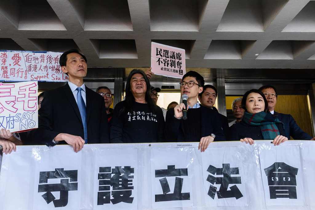 Elected pro-democracy lawmakers (L-R) Edward Yiu, (Long Hair) Leung Kwok-hung, Nathan Law, and Lau Siu-lai hold a banner outside the High Court before facing a judicial review into whether they should be disqualified from their Legislative Council seats, 