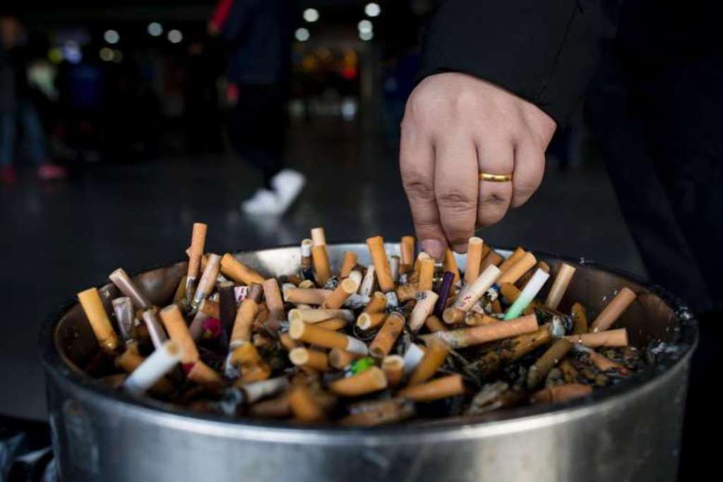 A man grinds out his cigarette in an ashtray at a Shanghai railway station on Feb 28, 2017.PHOTO: AFP.
